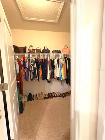 a view of walk in closet with clothes and shoes