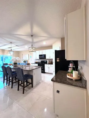 a kitchen with stainless steel appliances granite countertop a stove top oven a dining table and chairs with wooden floor