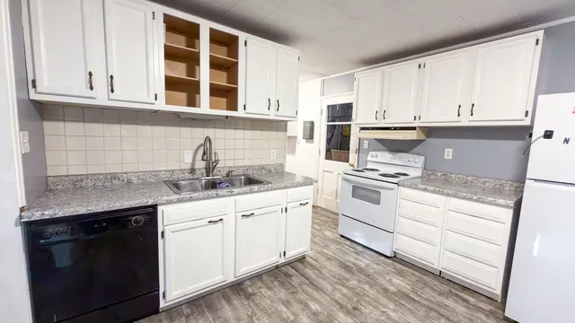 a kitchen with granite countertop white cabinets and white appliances