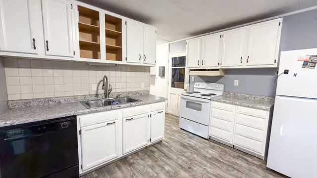 a kitchen with granite countertop white cabinets and white appliances