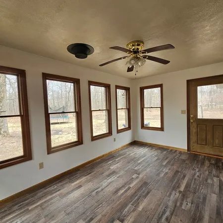 a view of an empty room with a window and wooden floor