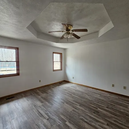 a view of empty room with wooden floor and fan