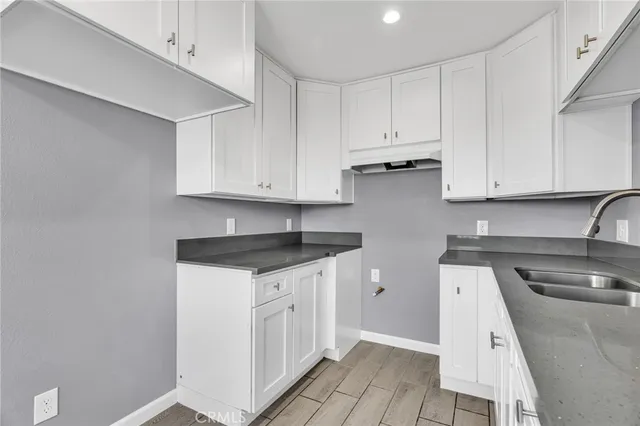 a kitchen with granite countertop white cabinets and sink