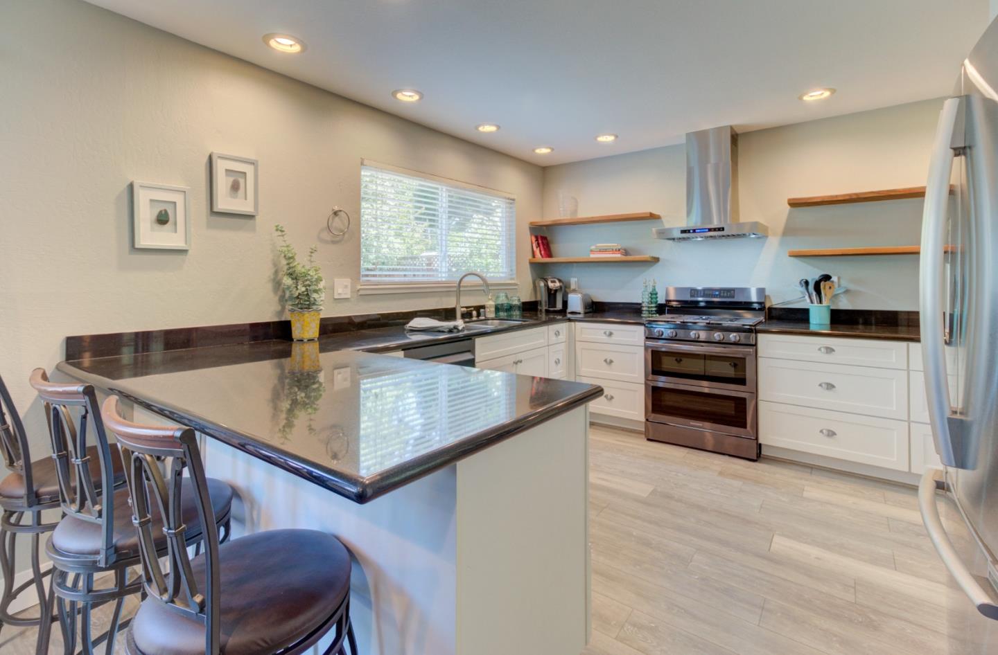 15120 Venetian Way Morgan Hill, CA 95037 - Photo 7 of 39 a kitchen with stainless steel appliances granite countertop a stove top oven a sink a dining table and chairs