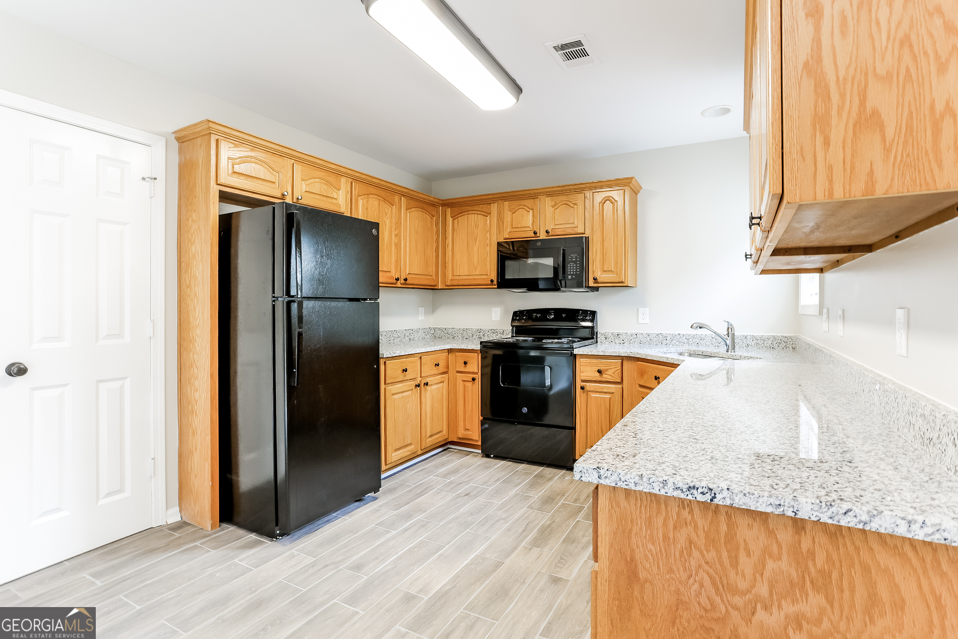 147 Portland Road Aragon, GA 30104 - Photo 7 of 17 a kitchen with stainless steel appliances granite countertop a refrigerator a stove and a sink with wooden floor