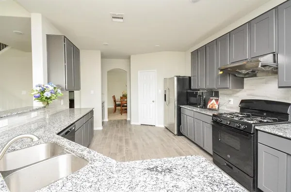 a kitchen with granite countertop a sink stove and refrigerator