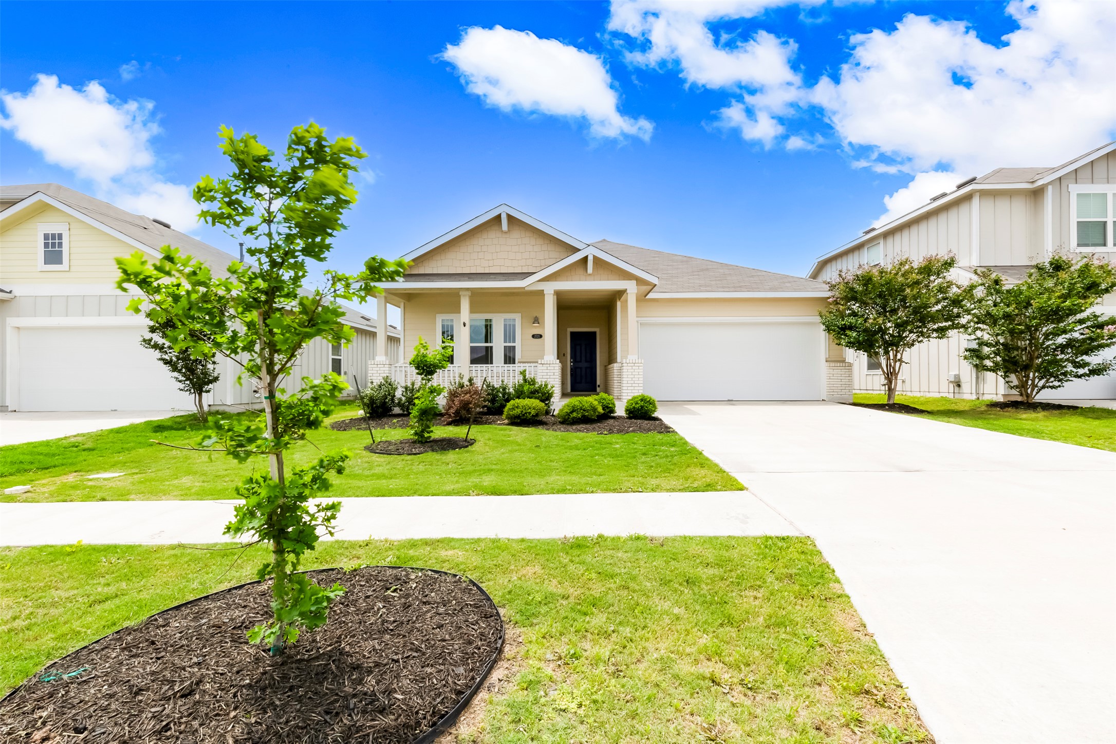 Single-story home featuring a covered front porch with white pillars, a two-car garage, and a light-toned exterior