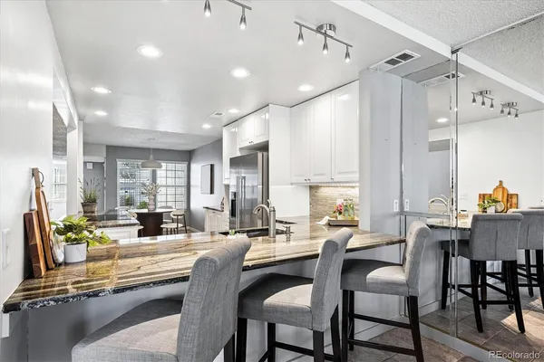 a dining room with stainless steel appliances kitchen island granite countertop a table chairs and view living room