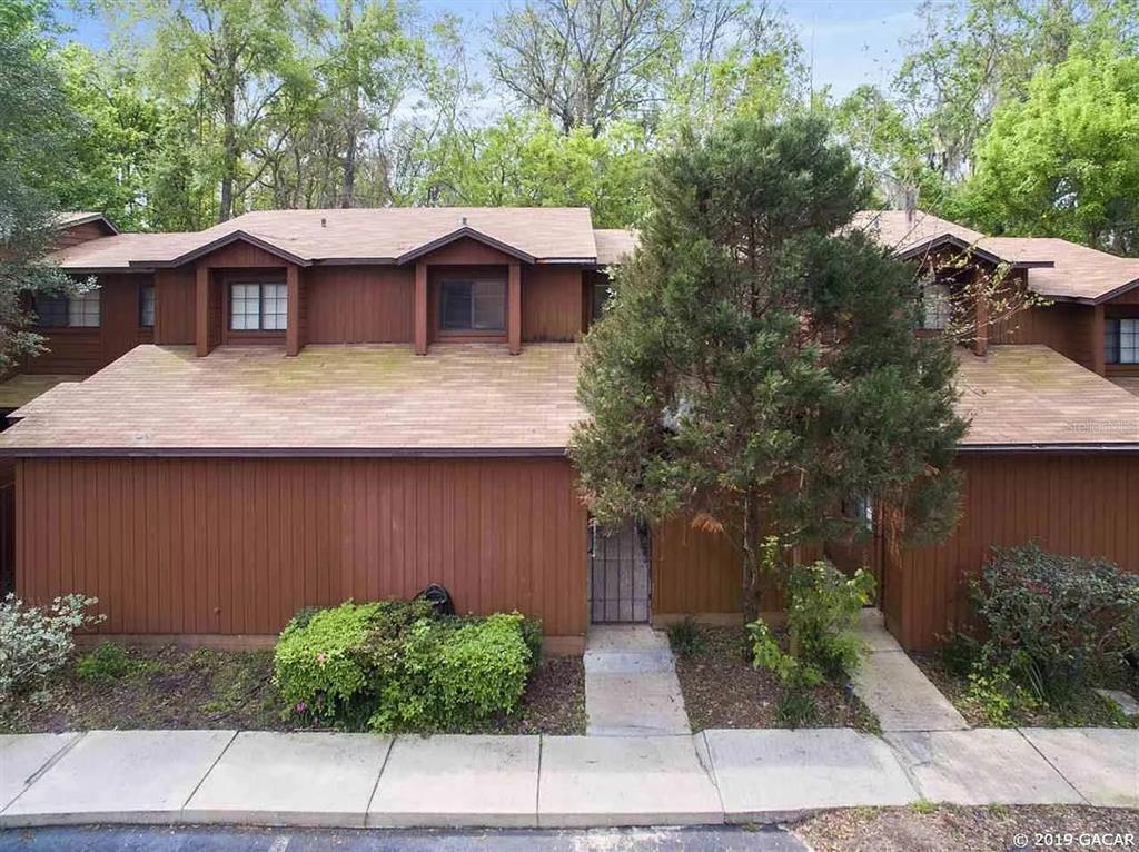 a view of a house with a yard plants and large tree