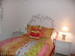 519 Roma Court, Unit 207 Naples, FL 34110 - Photo 5 of 8 a bedroom with a bed and a lamp on dresser