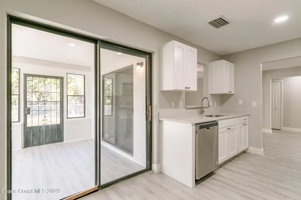 a kitchen with granite countertop a refrigerator a sink and white cabinets
