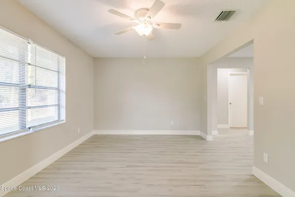 a view of an empty room with a window and a ceiling fan