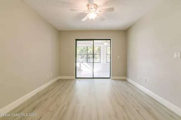 an empty room with wooden floor chandelier fan and windows