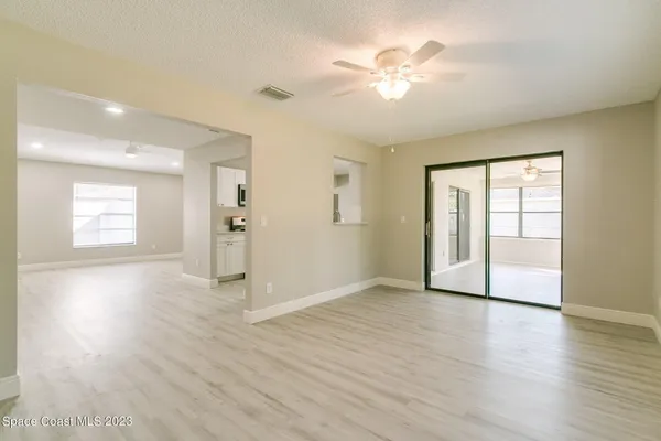 a view of an empty room with a window and wooden floor