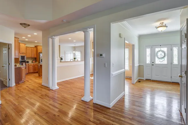 an empty room with wooden floor fireplace and windows