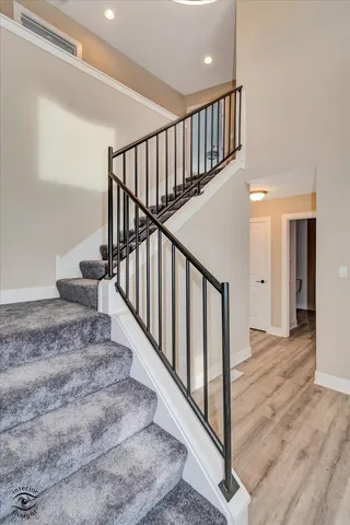 a view of staircase with lots of frames on wall and wooden floor