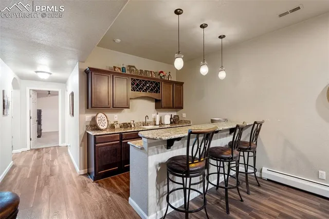 a open kitchen with stainless steel appliances granite countertop a stove top oven a sink a dining table and chairs with wooden floor