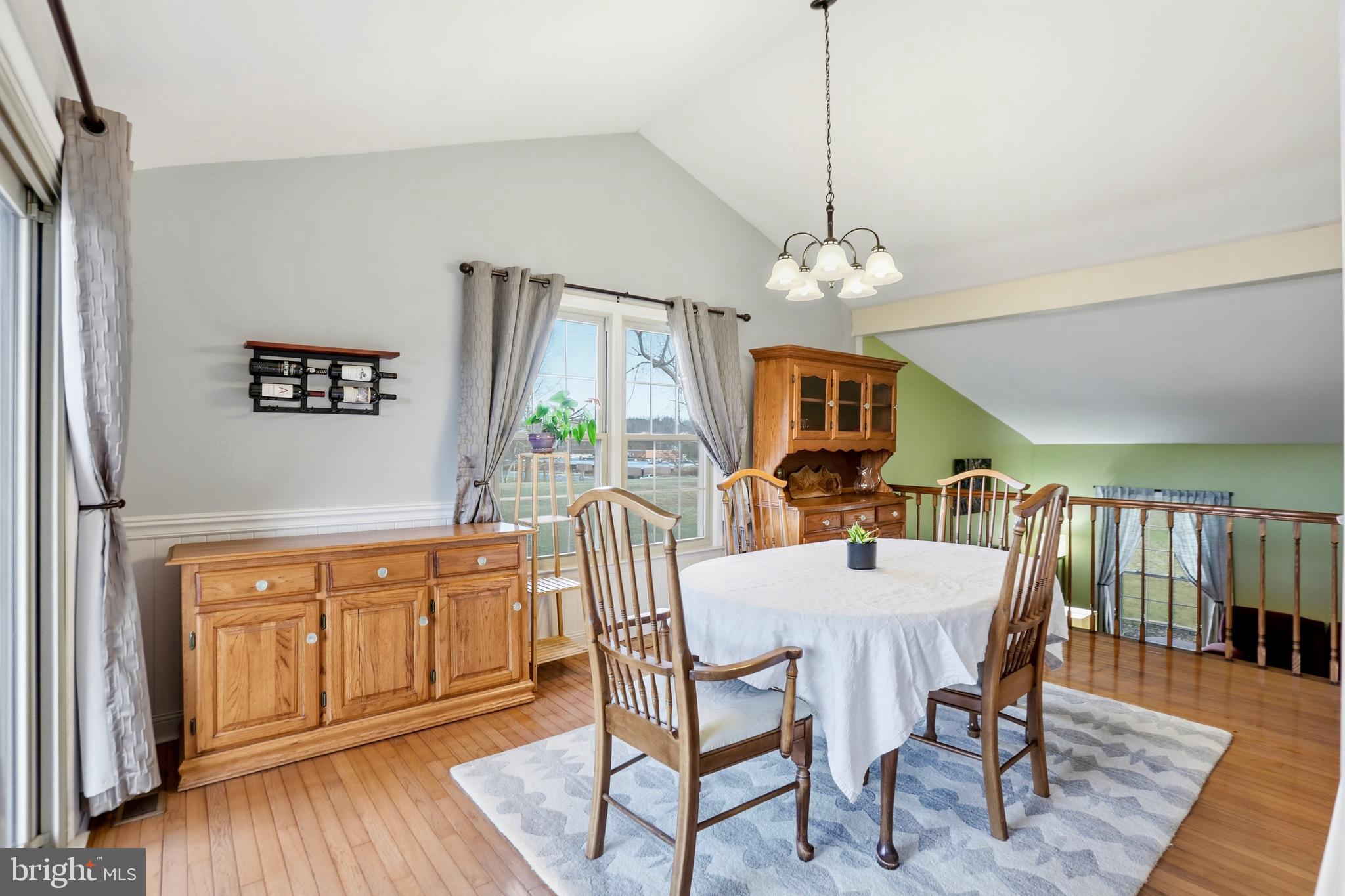 4708 Summit Point Road Charles Town, WV 25414 - Photo 7 of 49 a dining room with wooden floor a chandelier a wooden table and chairs