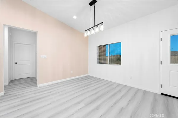 a view of an empty room with wooden floor and a ceiling fan
