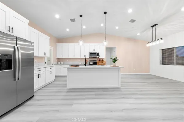 a large kitchen with kitchen island a sink stainless steel appliances and white cabinets