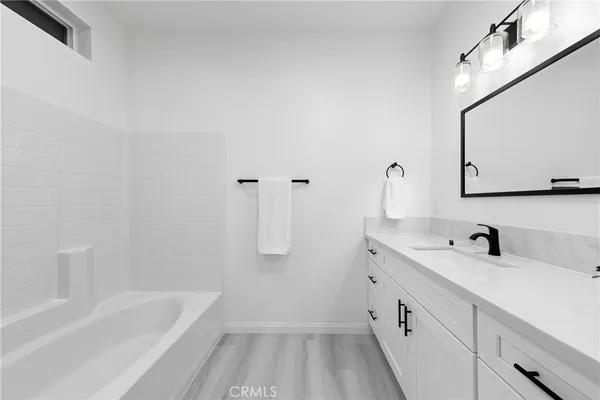 a bathroom with a bathtub a sink a mirror a shower and vanity