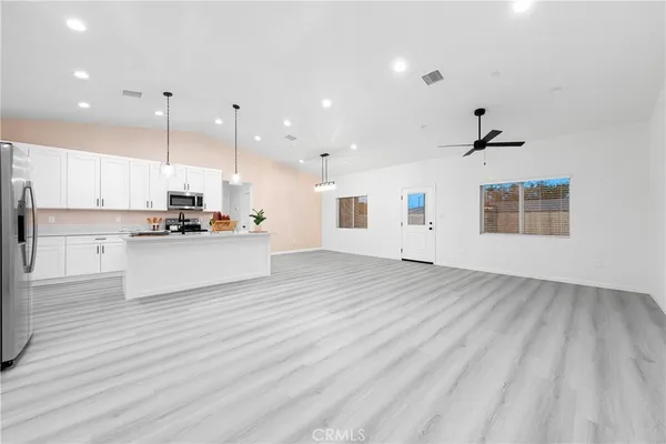 a view of a kitchen with kitchen island a sink stainless steel appliances and cabinets