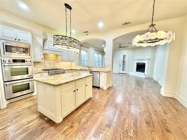 a kitchen with stainless steel appliances granite countertop a stove oven and a wooden floor