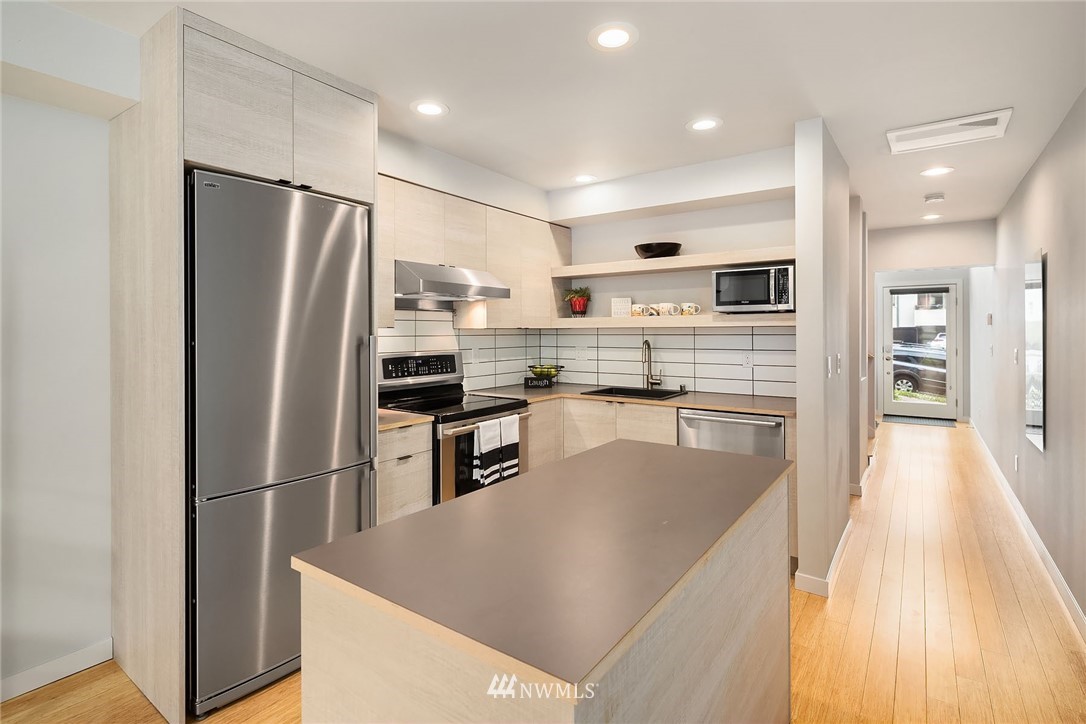 983 North 45th Street Seattle, WA 98103 - Photo 9 of 32 a kitchen with stainless steel appliances granite countertop a refrigerator a stove and a sink
