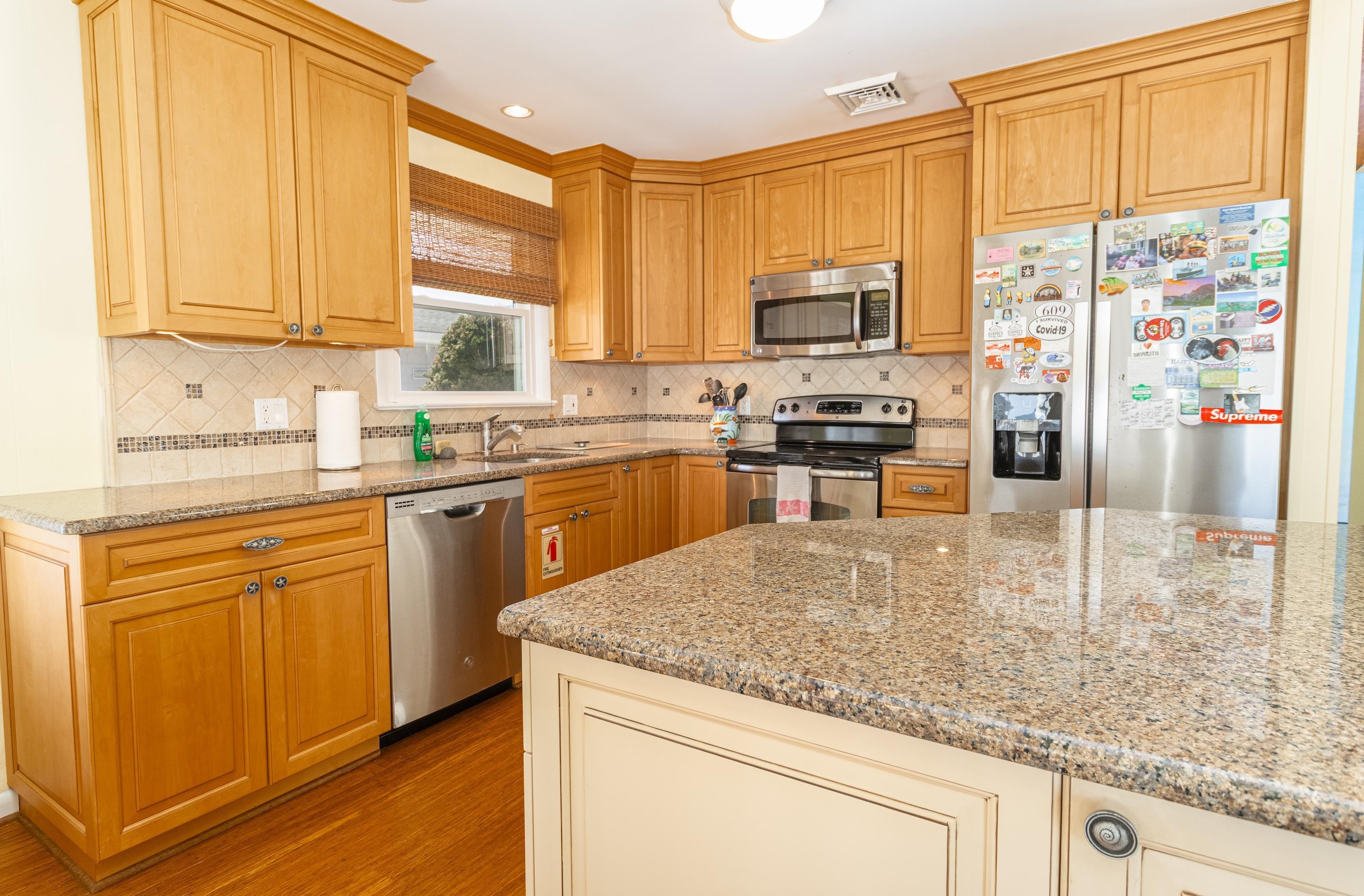 181 7th Street Avalon, NJ 08202 - Photo 12 of 29 a kitchen with stainless steel appliances granite countertop a stove top oven a sink dishwasher and microwave with wooden floor