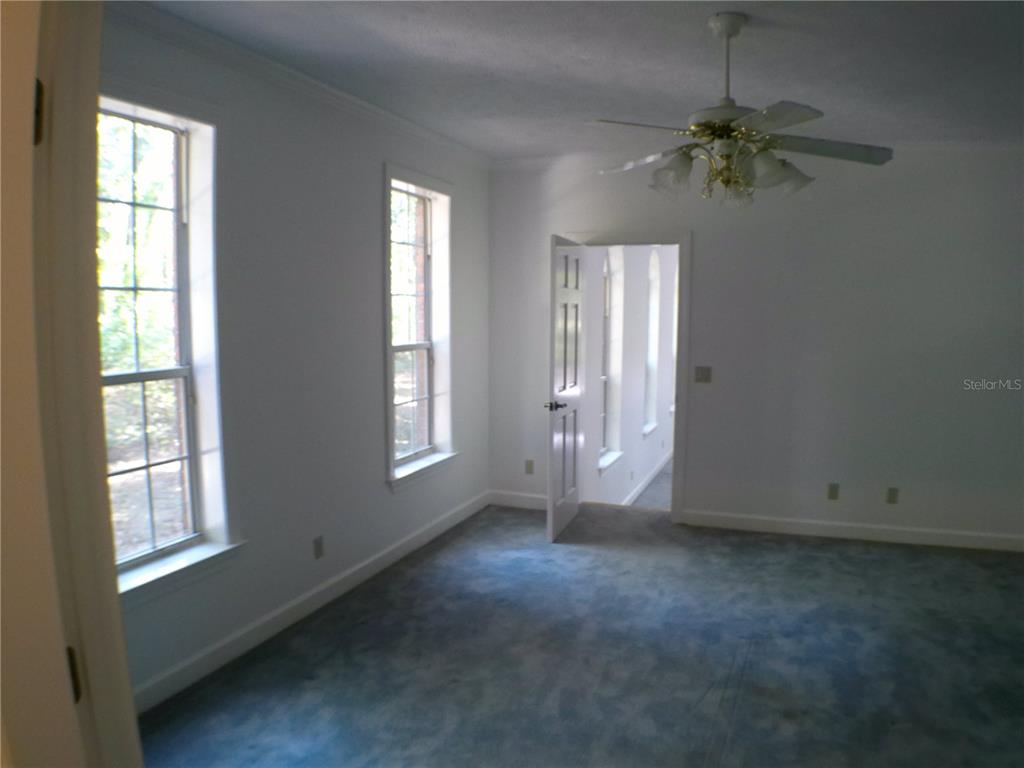 415 Southeast 123rd Street Road Ocala, FL 34480 - Photo 10 of 50 an empty room with windows and chandelier fan