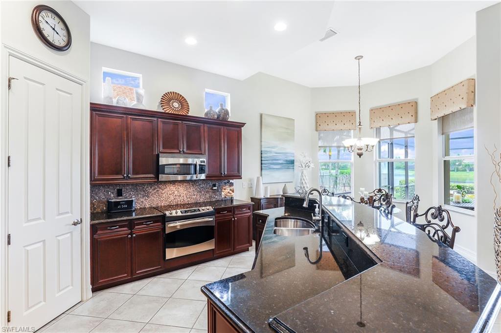 6581 Caldecott Drive Naples, FL 34113 - Photo 19 of 34 a kitchen with granite countertop a stove a sink and a refrigerator