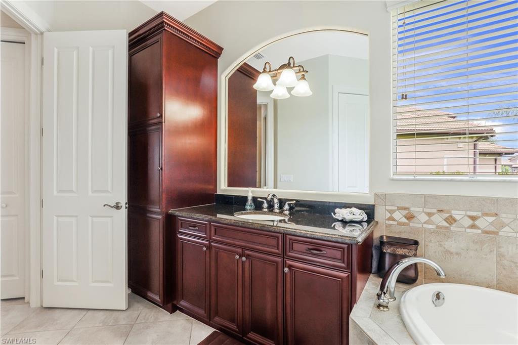 6581 Caldecott Drive Naples, FL 34113 - Photo 22 of 34 a bathroom with a sink and mirror with bathtub