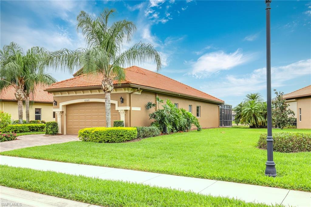 6581 Caldecott Drive Naples, FL 34113 - Photo 3 of 34 a front view of a house with a yard and garage