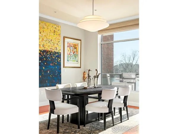 a dining room with wooden floor a chandelier a glass table and chairs