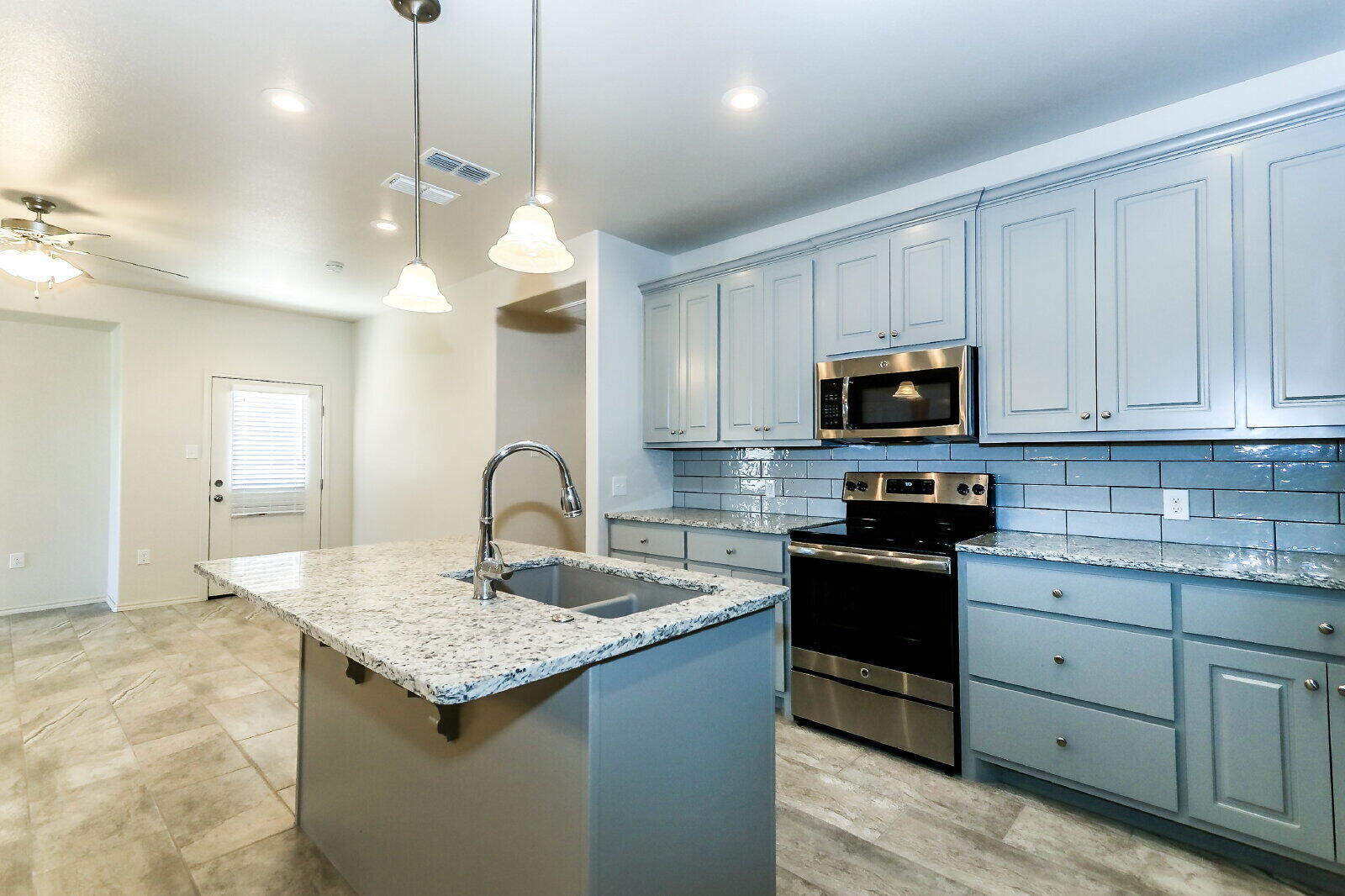 6903 67th Street, Unit A Lubbock, TX 79424 - Photo 12 of 32 a kitchen with kitchen island granite countertop stainless steel appliances a stove sink microwave and cabinets