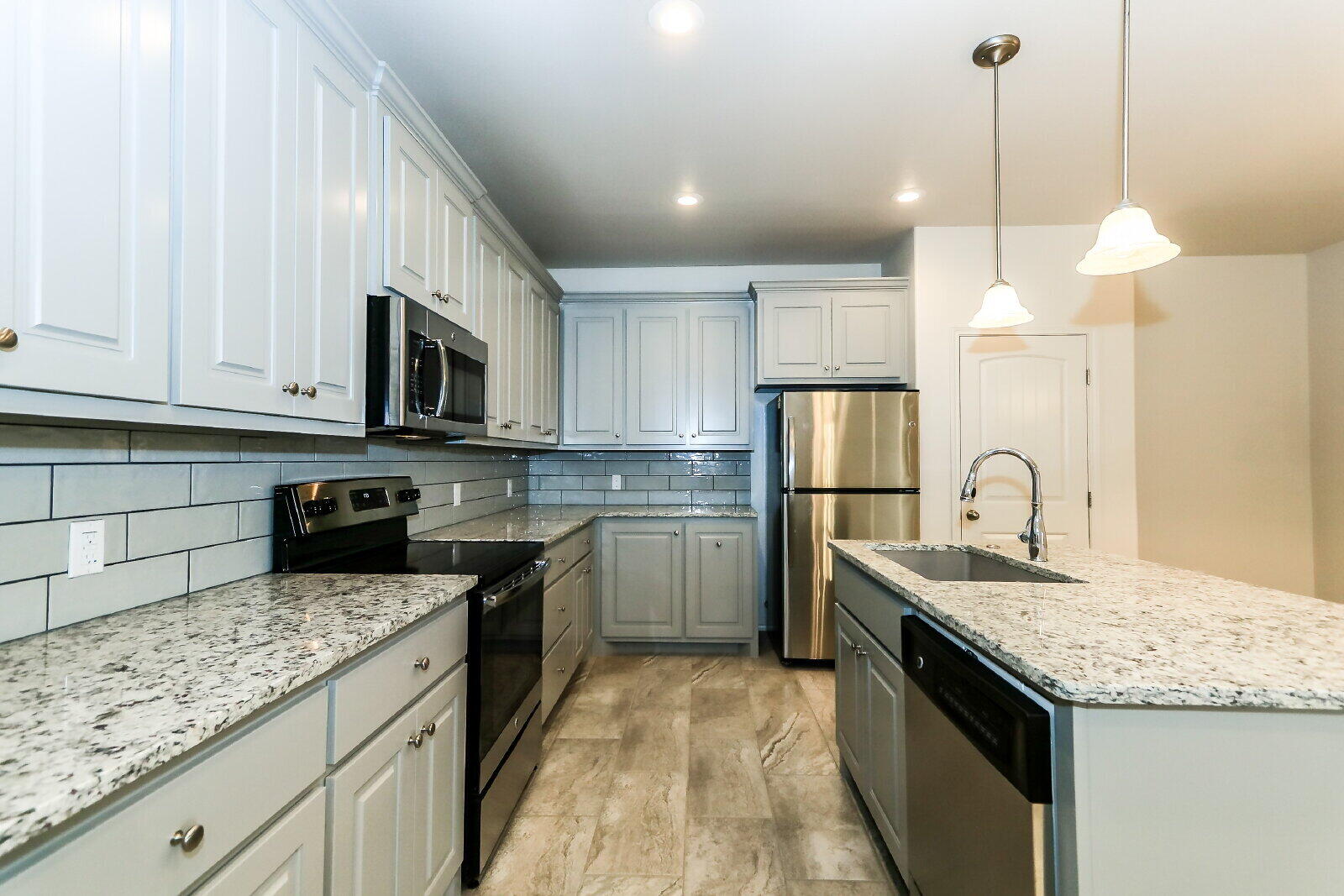 6903 67th Street, Unit A Lubbock, TX 79424 - Photo 9 of 32 a kitchen with kitchen island granite countertop a sink a counter top space stainless steel appliances and cabinets