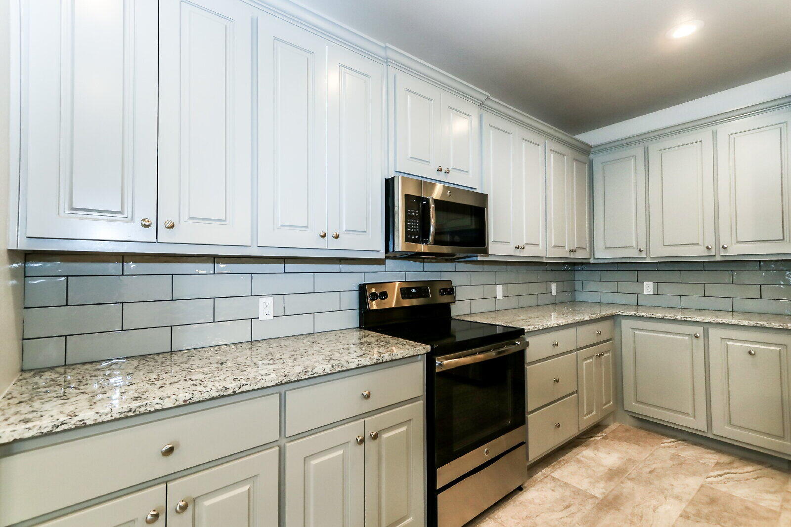 6903 67th Street, Unit A Lubbock, TX 79424 - Photo 10 of 32 a kitchen with granite countertop white cabinets sink and stainless steel appliances