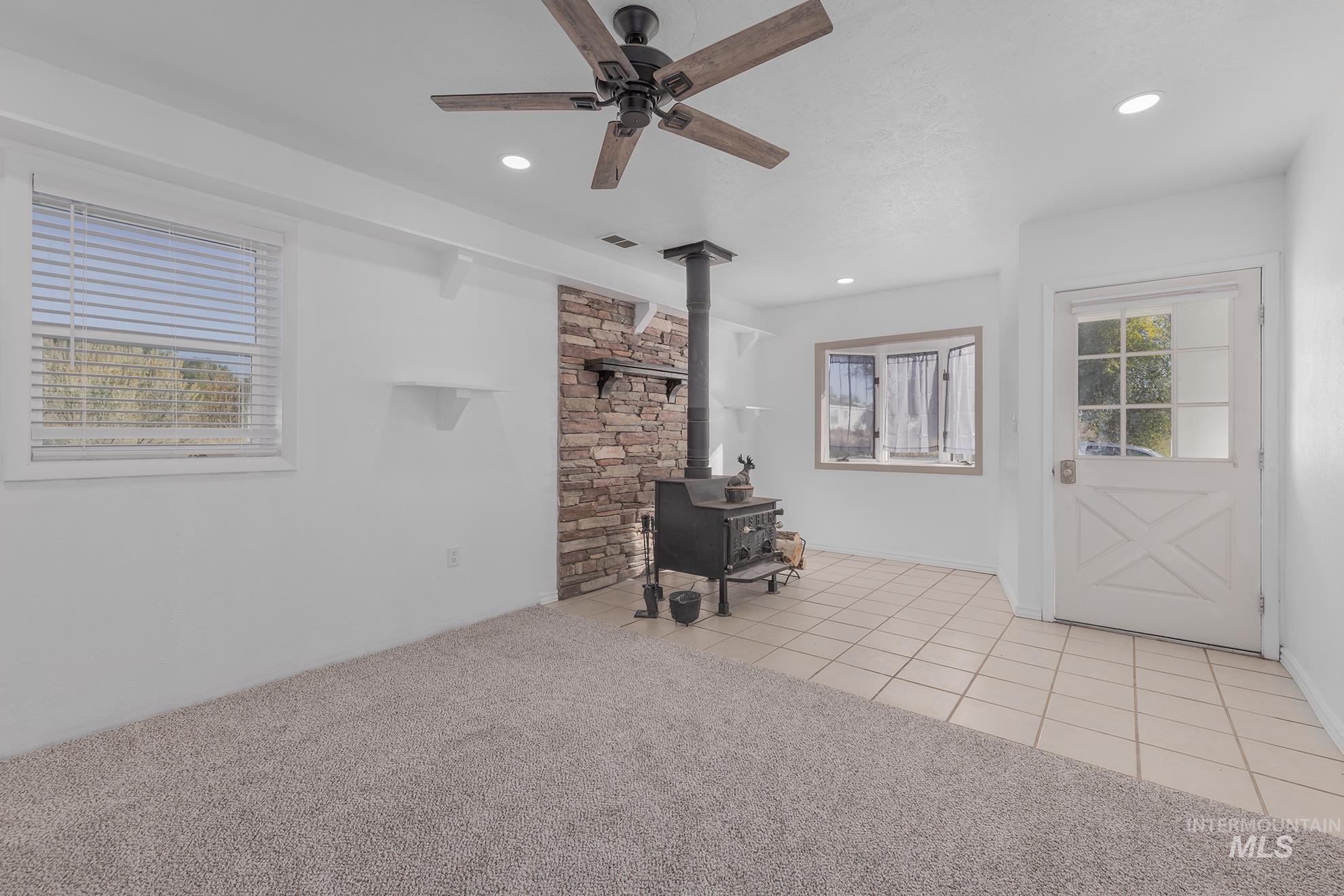 28552 Market Road Caldwell, ID 83607 - Photo 13 of 50 Living room with a wood stove, light tile patterned floors, light carpet, ceiling fan, and recessed lighting