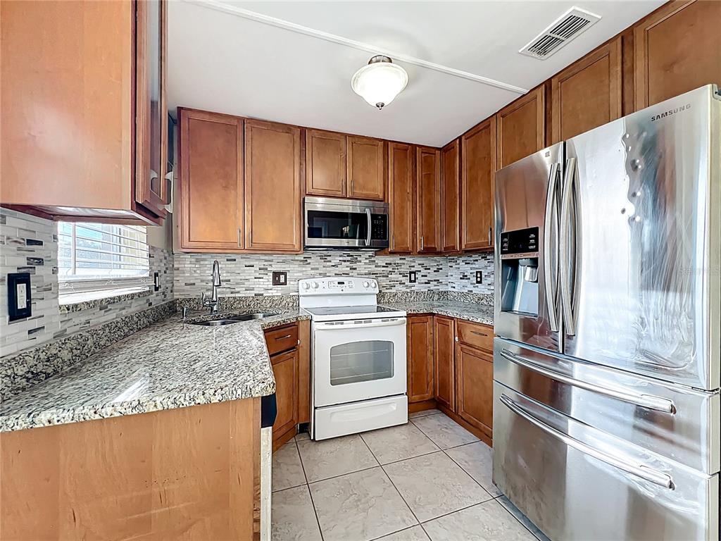 12295 Ridge Road Largo, FL 33778 - Photo 7 of 31 a kitchen with granite countertop a refrigerator sink and microwave