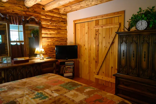 a bedroom with a bed and a flat tv screen on dresser