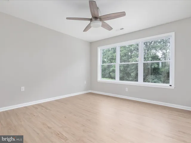 an empty room with wooden floor a ceiling fan and closet