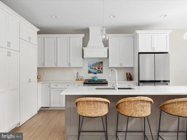 a kitchen with kitchen island granite countertop wooden cabinets a stove a sink and a white cabinets