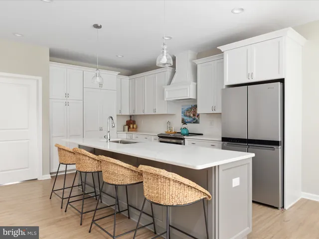 a kitchen with stainless steel appliances a white table chairs and a refrigerator