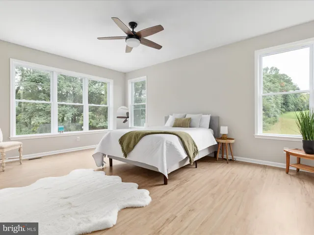 a spacious bedroom with a bed a large window with wooden floor and windows