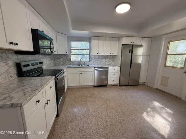 a kitchen with stainless steel appliances granite countertop a stove a sink dishwasher a refrigerator and a microwave