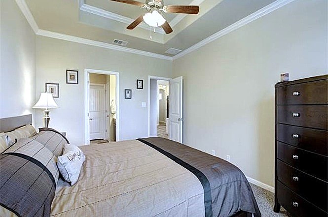 14001 Avery Ranch Boulevard, Unit 801 Austin, TX 78717 - Photo 6 of 26 A tranquil bedroom retreat features a tray ceiling with crown molding and a prominent ceiling fan.