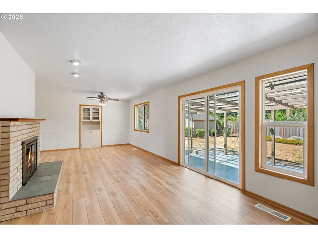 a view of empty room with wooden floor and fireplace
