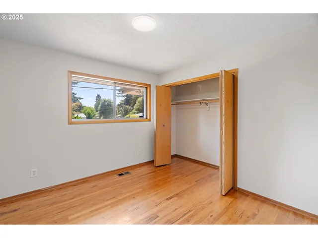 an empty room with wooden floor and window