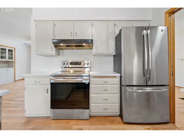 a kitchen with granite countertop a refrigerator stove and cabinets