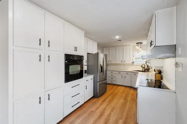 a kitchen with stainless steel appliances a refrigerator sink and white cabinets